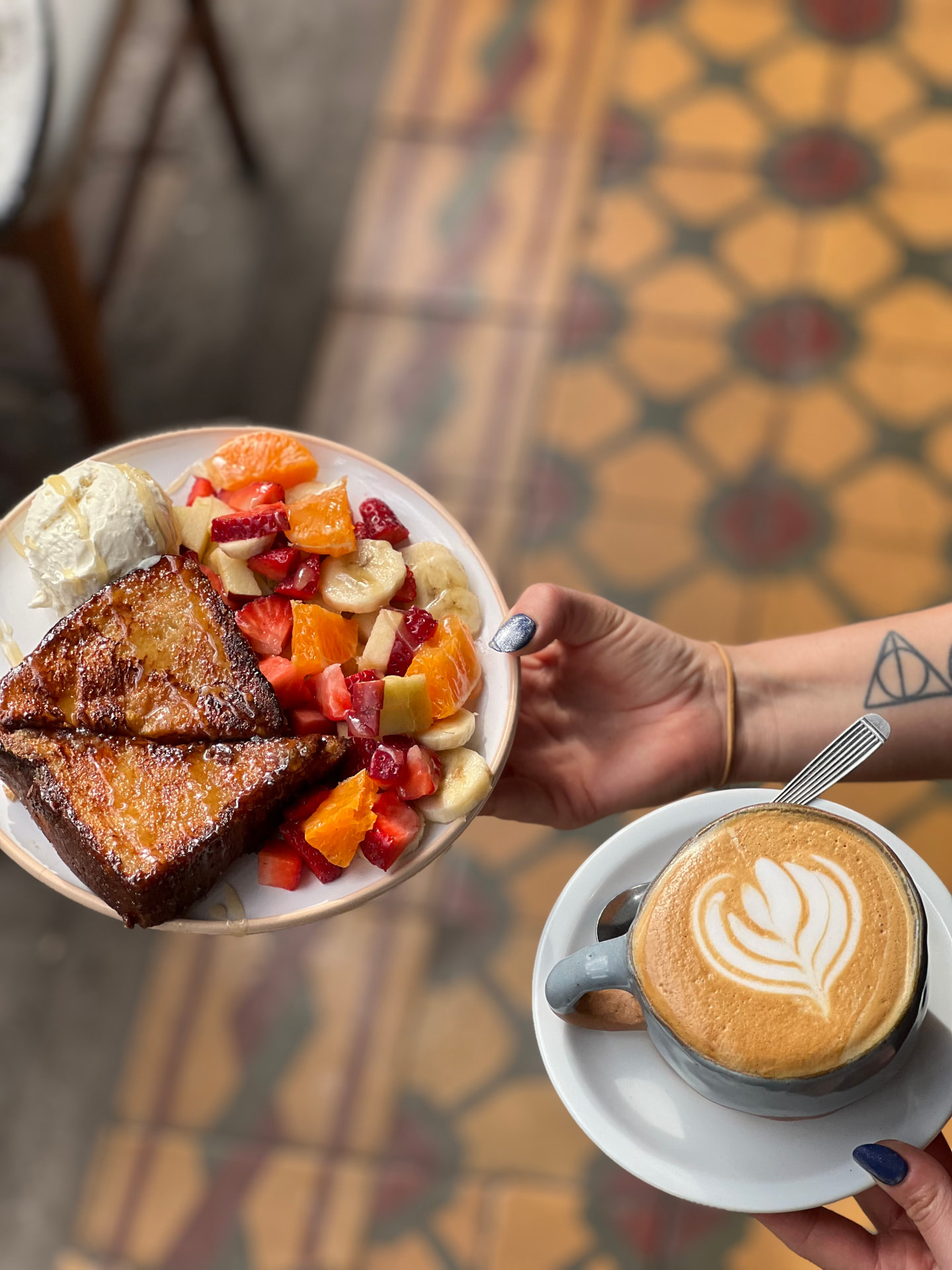 Plato de tostadas francesas con frutas y un café servido en Boulevard Deli Café