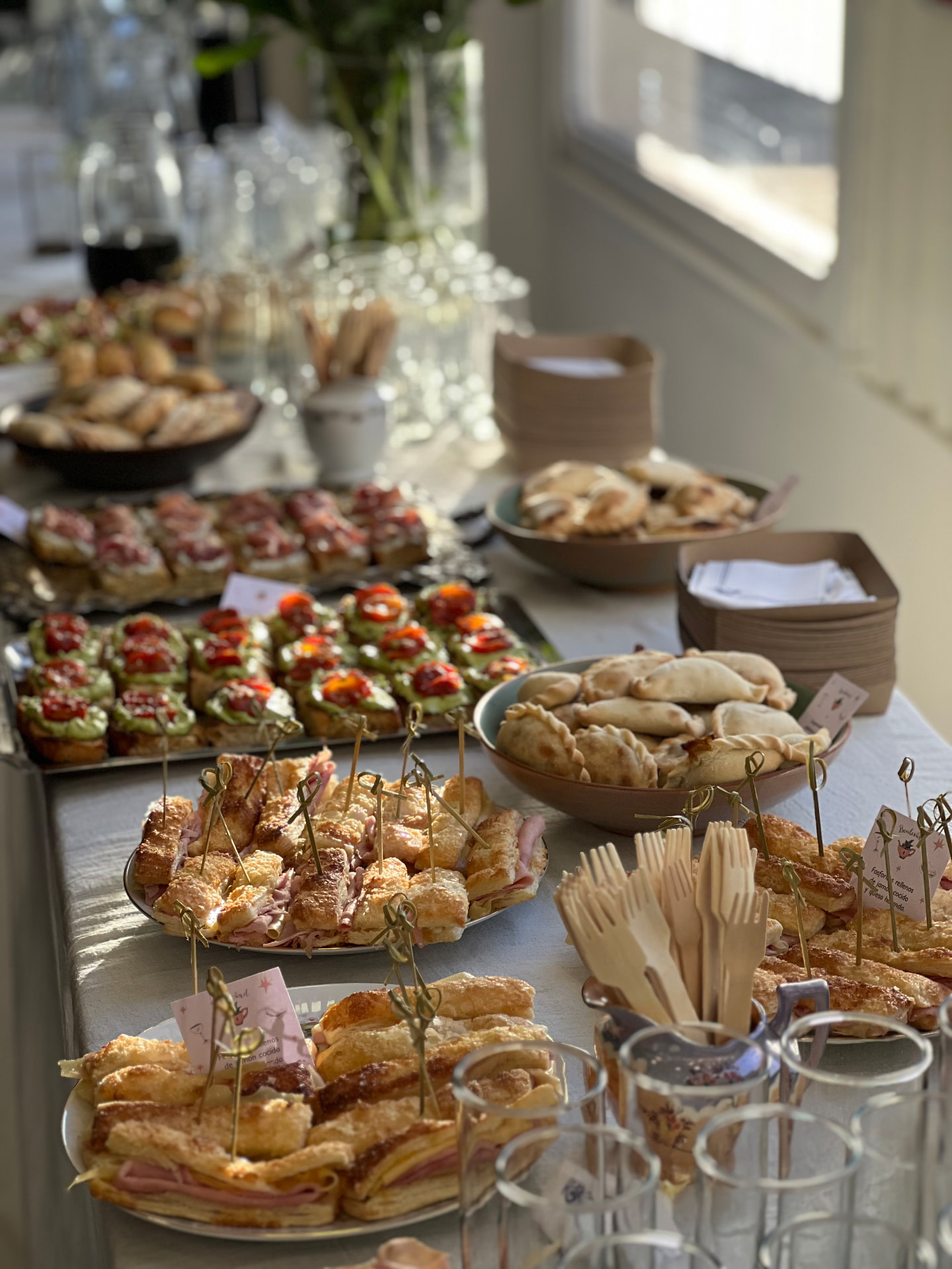 Mesa de catering servida con sándwiches, tartas, bocaditos y jugos